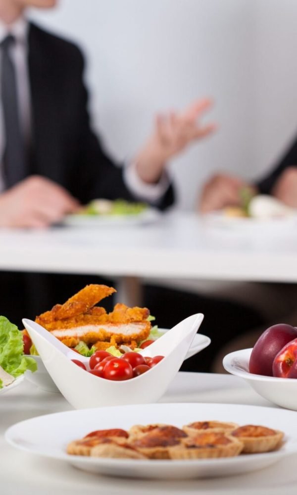 Catered corporate lunch platters with colleagues meeting in the background