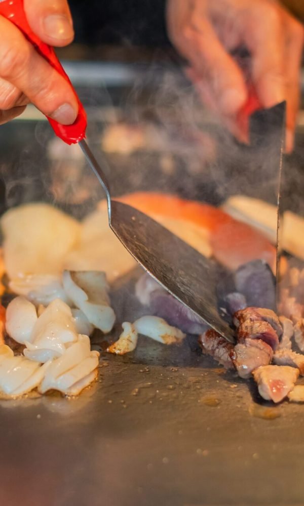 Chef with a spatula cooking teppanyaki on a hibachi grill table
